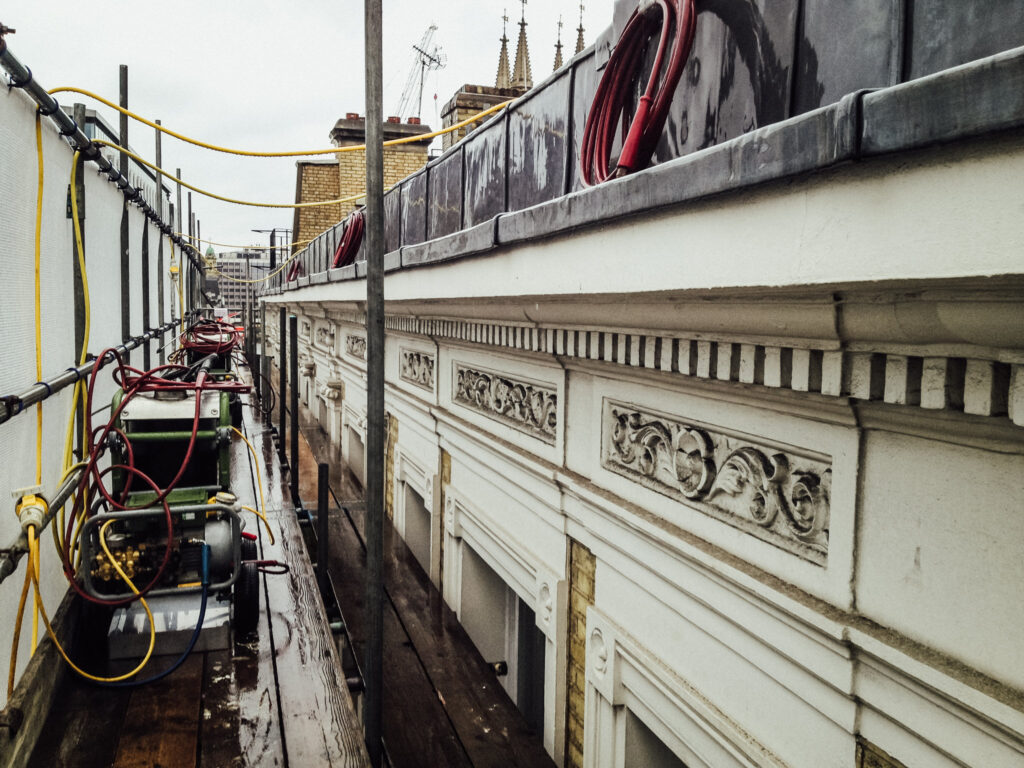 scaffold with cleaning equipment on next to a white stone building that looks recently cleaned
