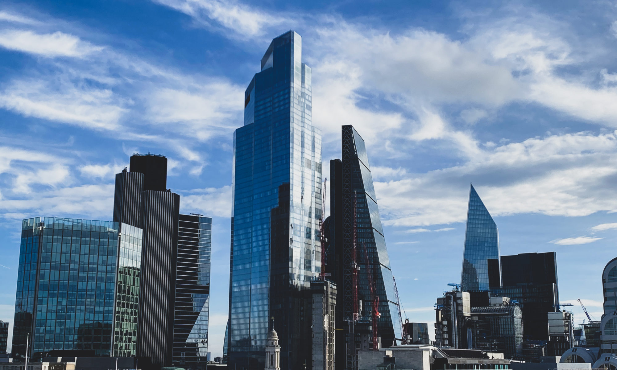 London skyline with skyscrapers against a bright blue sky, capturing iconic modern architecture.