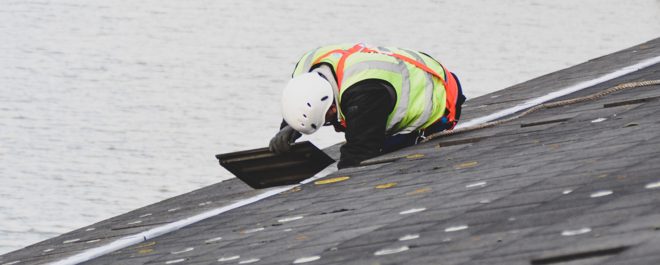 Person in high vis lifting a roof tile