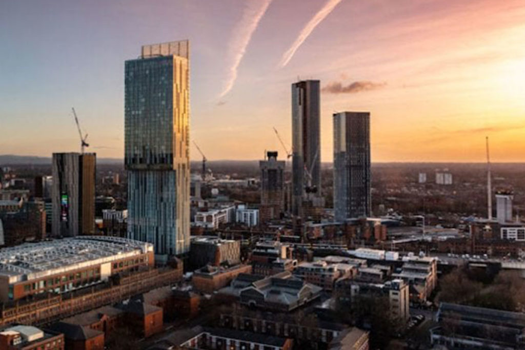 Sunset over Manchester skyline with modern skyscrapers and cranes, capturing urban growth and vibrant hues.