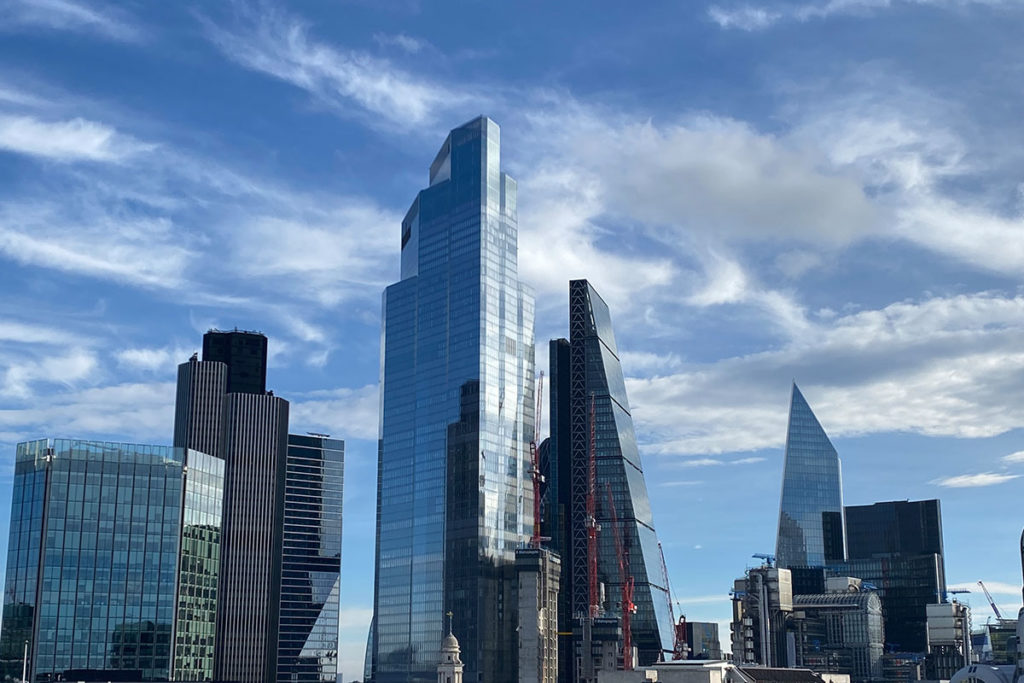 Modern London skyline with reflective skyscrapers under a vibrant blue sky, showcasing urban architecture.