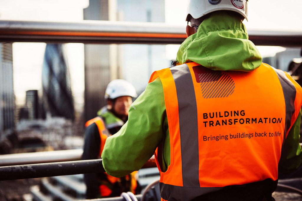Construction worker in orange vest, BUILDING TRANSFORMATION. Bringing buildings back to life, city skyline.