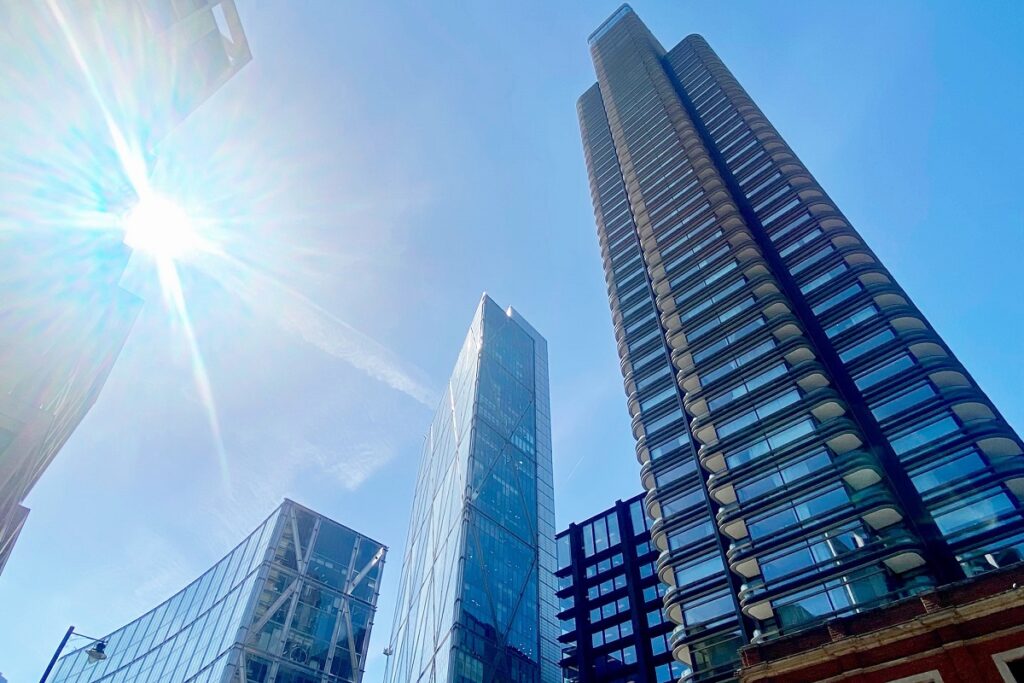 Sunlit modern skyscrapers against a clear blue sky, showcasing urban architecture and glass facades.