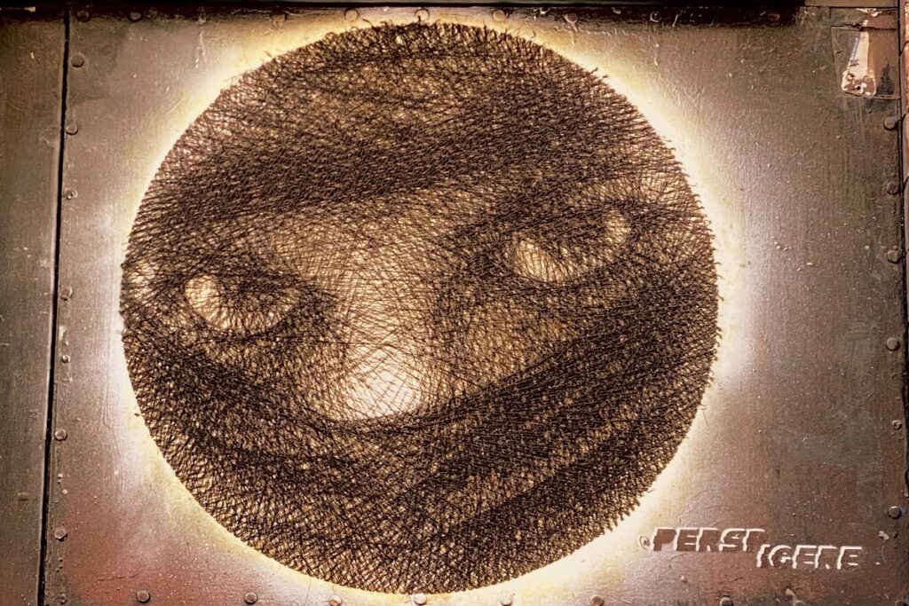 Textured circular artwork of intense eyes by artist Peestigrec on a distressed metal background.
