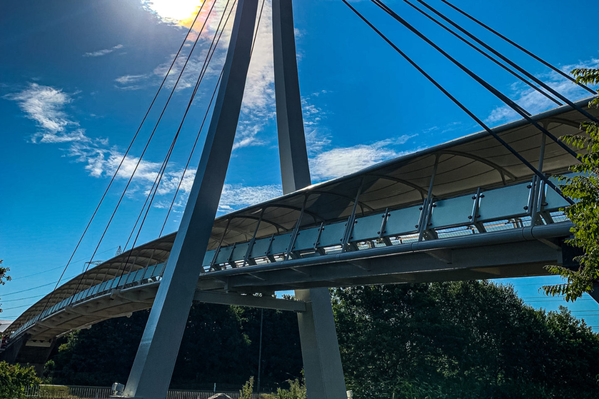 Modern suspension bridge against a bright blue sky, showcasing sleek design and architectural elegance.