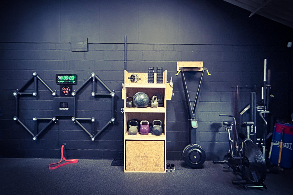 Modern gym with kettlebells, rowing machine, fitness timer, and wall-mounted exercise equipment.