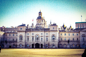 Historic Horse Guards Building in London with a clear blue sky and Union Jack flags.