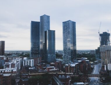 Modern skyscrapers towering over Manchester cityscape under an overcast sky at dusk.
