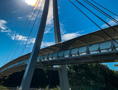 Modern suspension bridge against a bright blue sky, showcasing sleek design and architectural elegance.